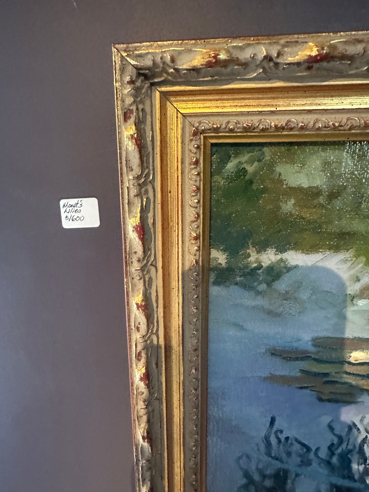 The ornate gold-framed surrounding the water lily paintings with a landscape in blue, green, and gray tones.